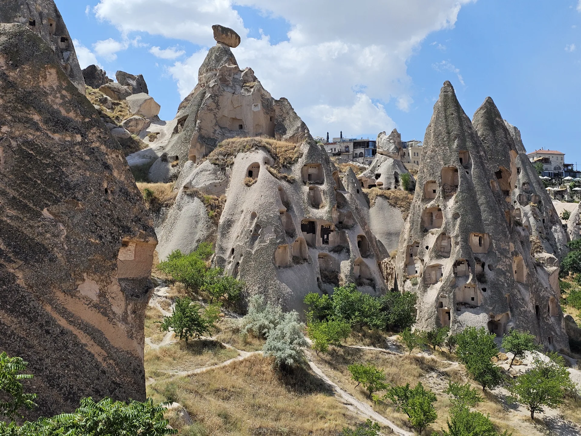 Fairy chimneys and rock-cut doorways beneath a blue sky