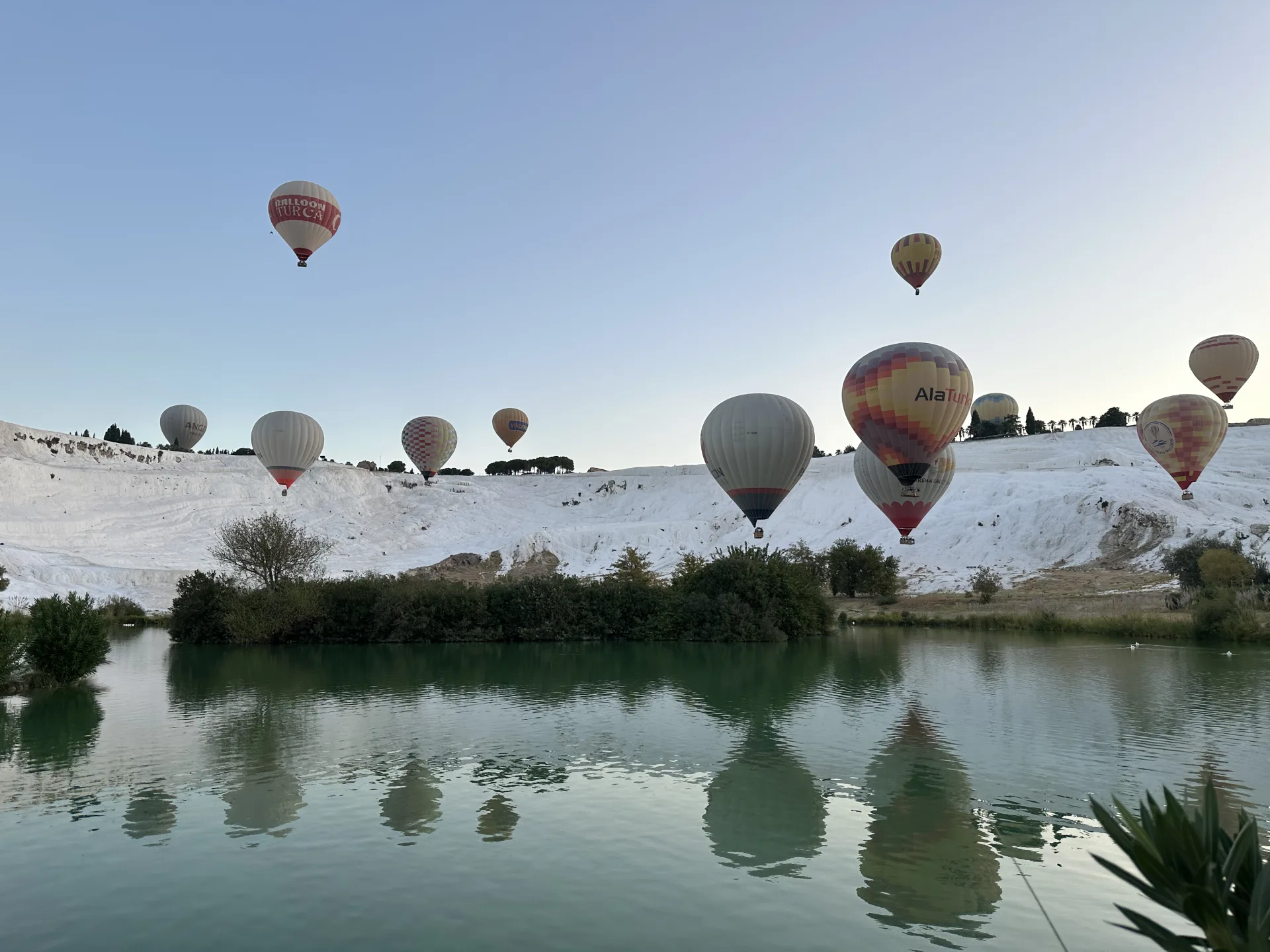 Balloons over Pamukkale’s travertines reflected in a lake