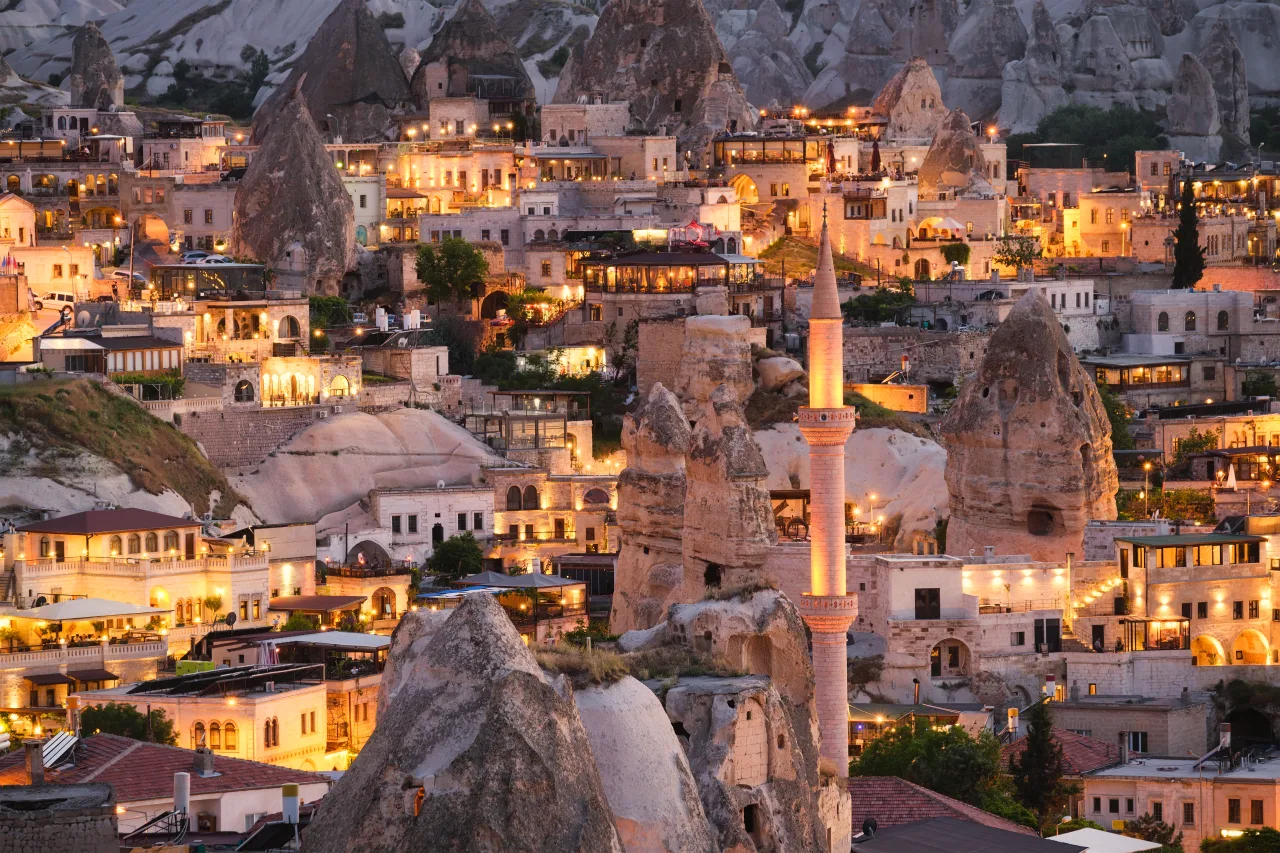 A Cappadocia town and rock-cut buildings lit at dusk