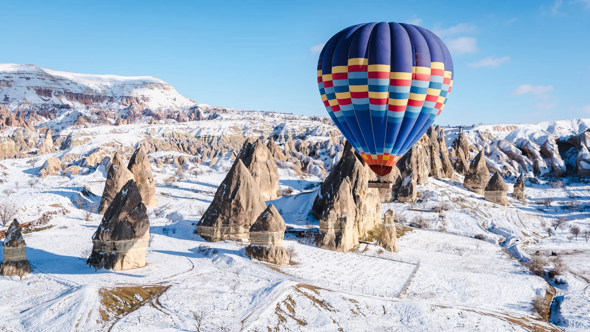 A balloon over snow-covered rock formations in Cappadocia