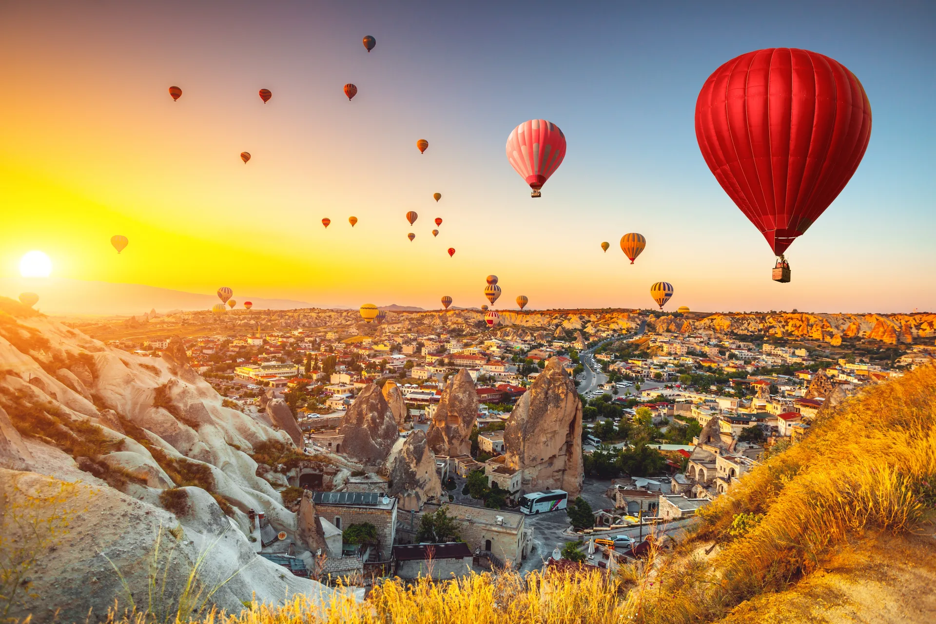Globos sobre el paisaje rocoso de Capadocia con luz dorada de la mañana
