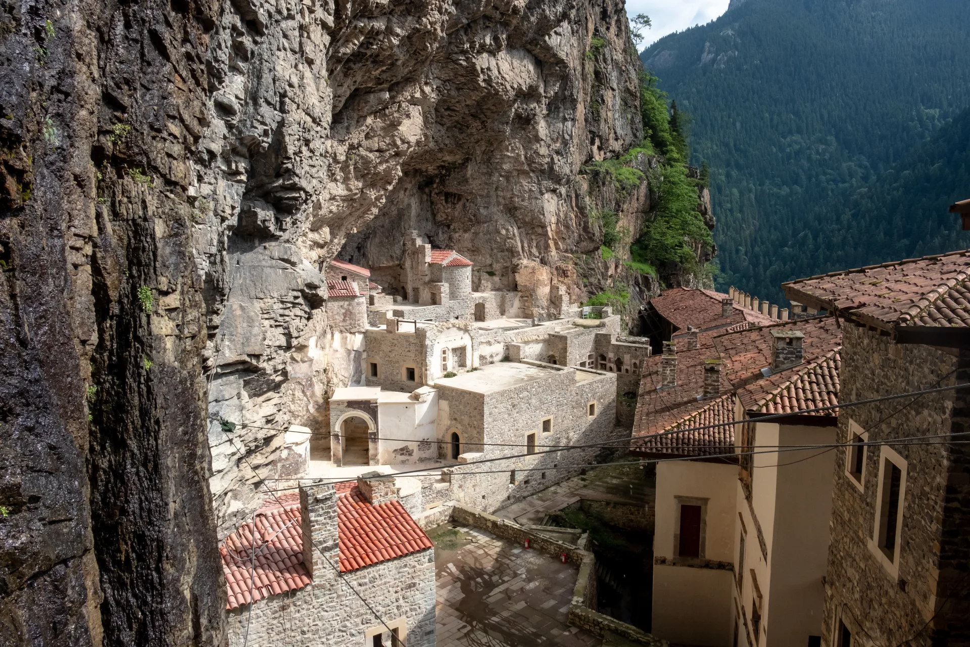 Sümela Monastery’s buildings beneath the cliff and forested mountains